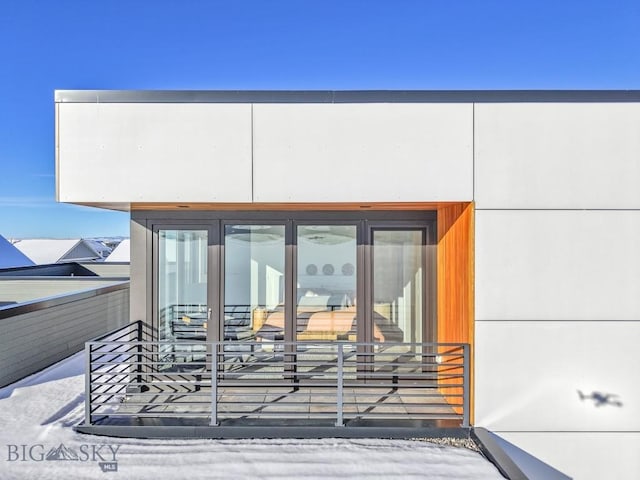 snow covered property entrance featuring a balcony