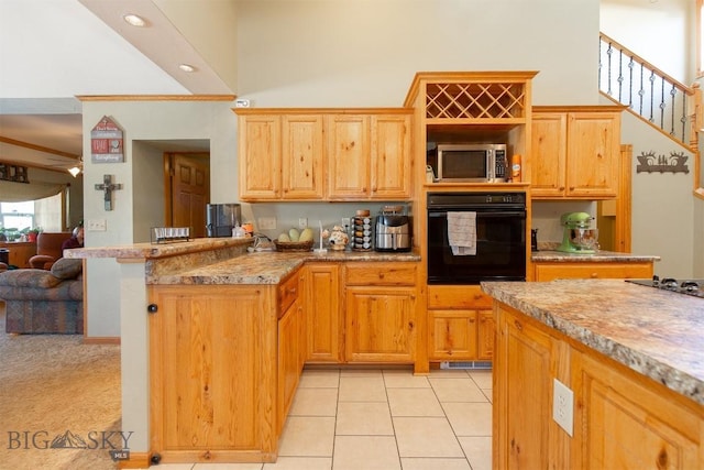 kitchen with light tile patterned floors, black appliances, a peninsula, and a towering ceiling
