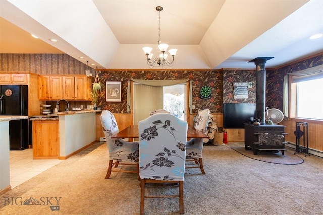 dining area featuring a wood stove, light colored carpet, wallpapered walls, recessed lighting, and a notable chandelier