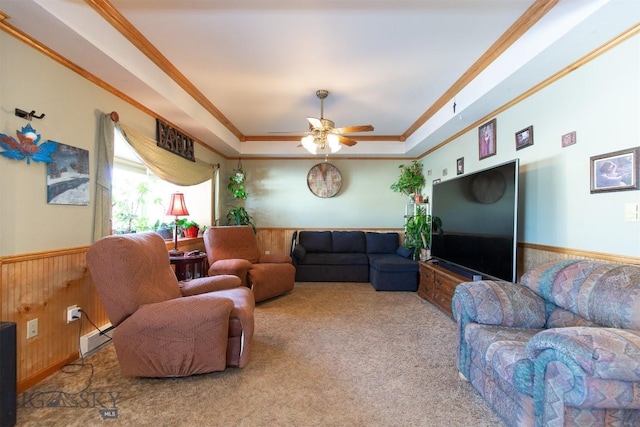 living area featuring carpet floors, wood walls, a wainscoted wall, crown molding, and a tray ceiling
