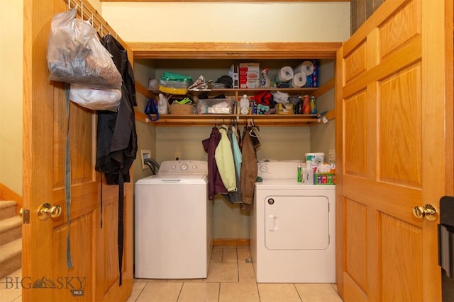 clothes washing area with light tile patterned floors, washer and dryer, and laundry area