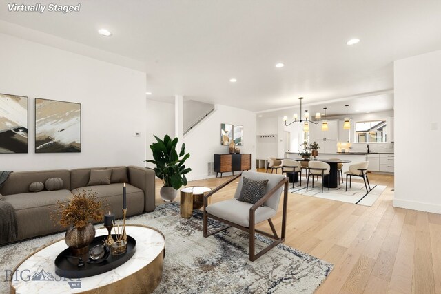 living room with an inviting chandelier and light hardwood / wood-style floors