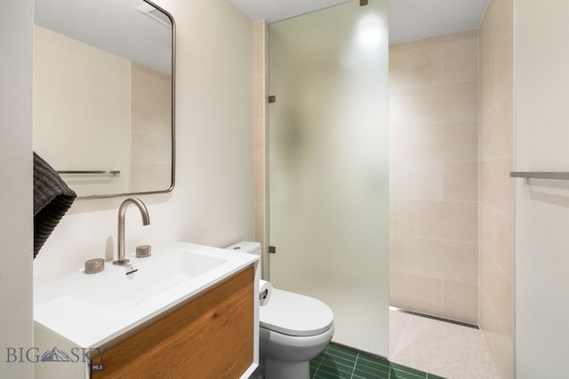 bathroom featuring toilet, a tile shower, and vanity