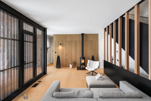 living room with light hardwood / wood-style floors and a wood stove