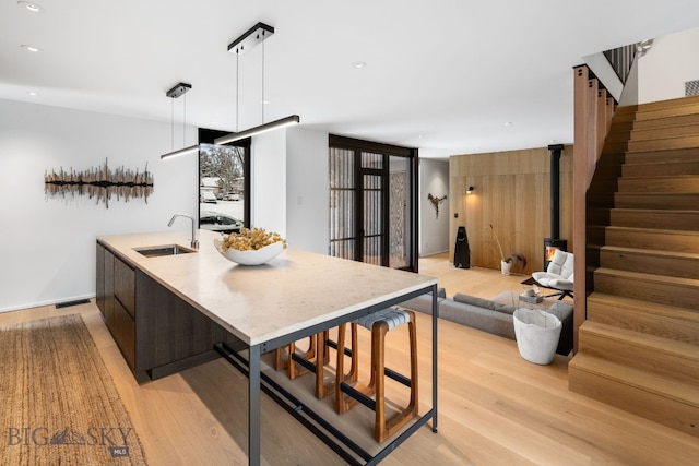 kitchen featuring sink, pendant lighting, light hardwood / wood-style flooring, and a kitchen island with sink