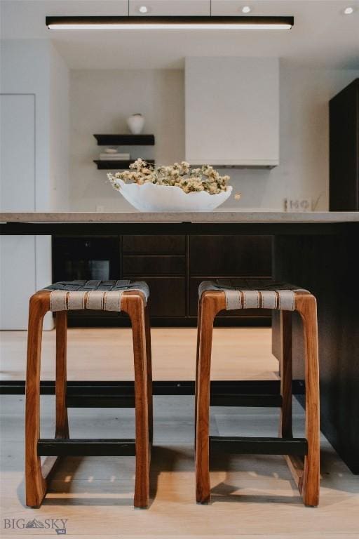 bar with white cabinetry and light hardwood / wood-style flooring