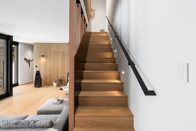 staircase with floor to ceiling windows and hardwood / wood-style flooring