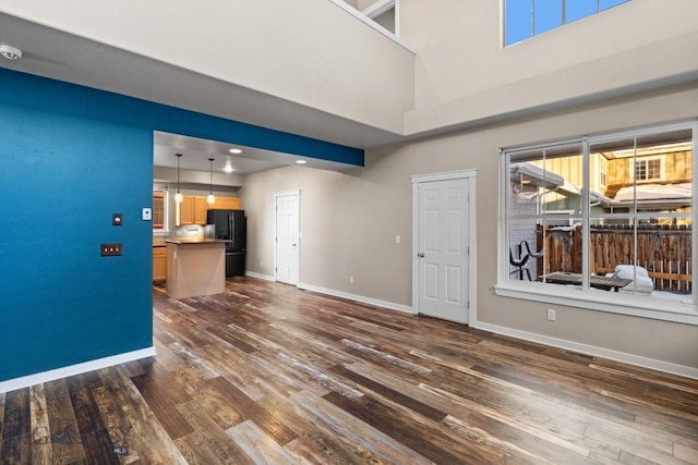 unfurnished living room with dark hardwood / wood-style flooring and a towering ceiling