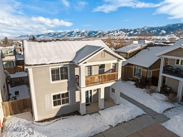 snow covered property with a mountain view and a balcony