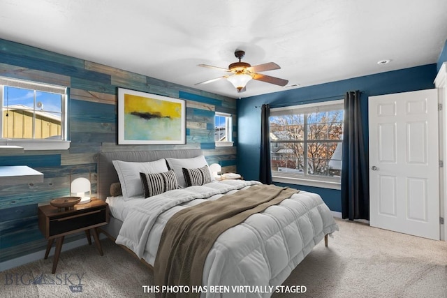 carpeted bedroom with ceiling fan and wood walls