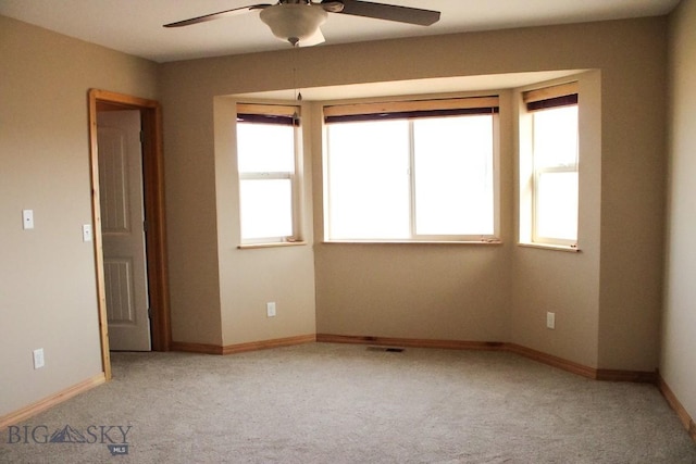 empty room with ceiling fan, carpet, visible vents, and baseboards