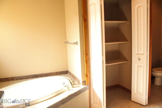 bathroom with a bath, toilet, and tile patterned floors