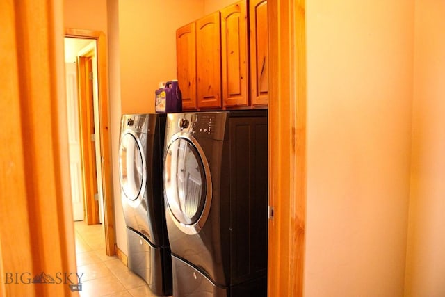 laundry area with light tile patterned flooring, cabinet space, and washing machine and clothes dryer