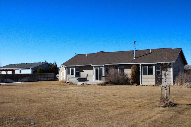 rear view of house featuring a lawn and fence