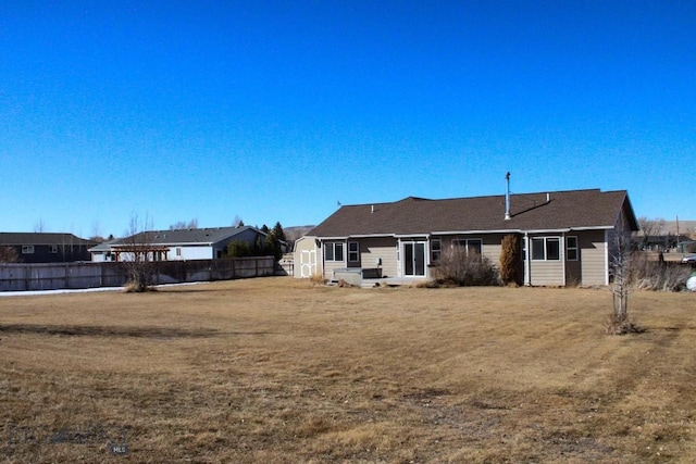 rear view of property with fence and a yard