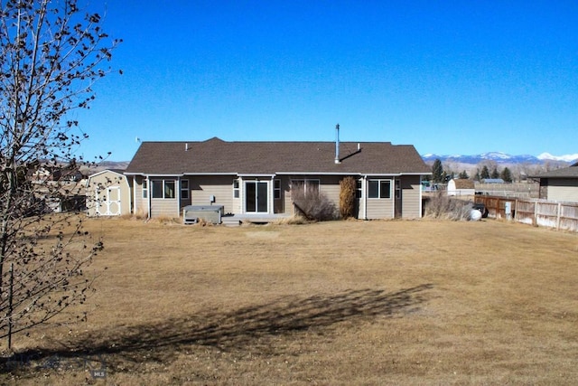 rear view of house featuring a lawn, fence, and a mountain view