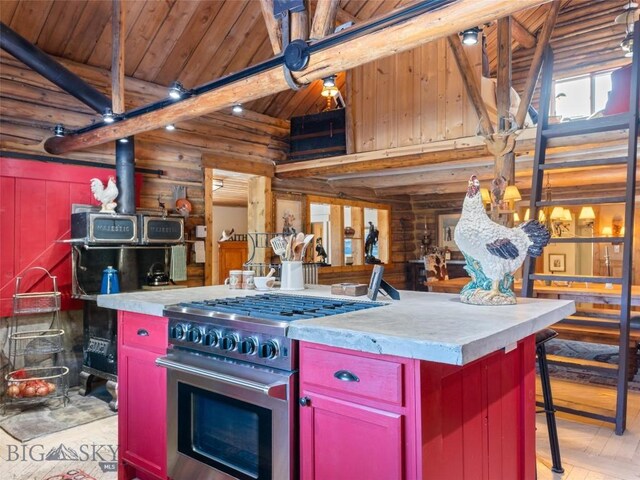 107 Dry Creek Trl, Ennis, MT 59729 - kitchen featuring red cabinets, rustic walls, stainless steel stove, high vaulted ceiling, and light wood-style flooring