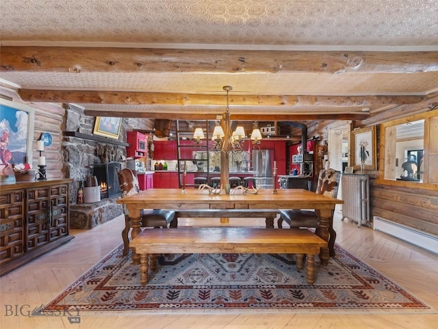 107 Dry Creek Trl, Ennis, MT 59729 - dining room with beam ceiling, hardwood / wood-style floors, a fireplace, a chandelier, and baseboard heating
