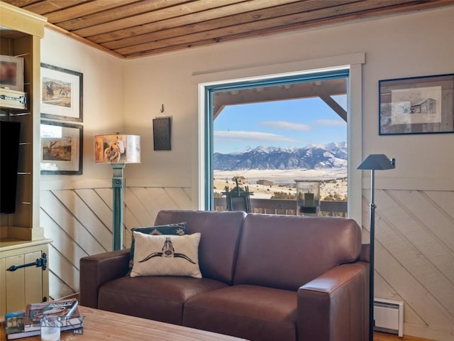 107 Dry Creek Trl, Ennis, MT 59729 - living area with a mountain view, a baseboard radiator, wooden ceiling, and a wainscoted wall