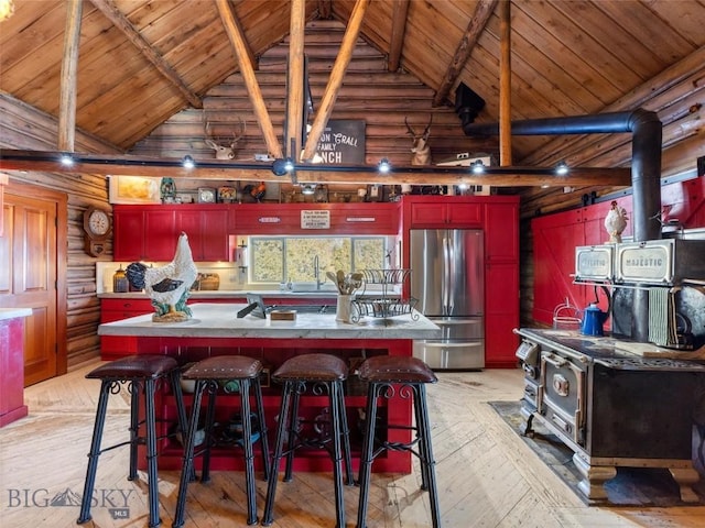 107 Dry Creek Trl, Ennis, MT 59729 - kitchen featuring freestanding refrigerator, a wood stove, log walls, light wood-style floors, and wood ceiling with exposed beams