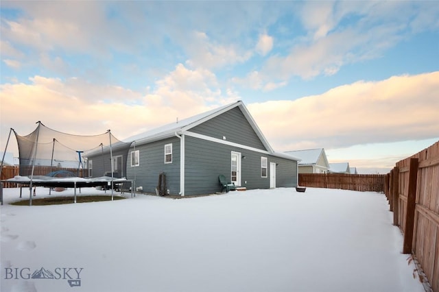 snow covered rear of property featuring a trampoline