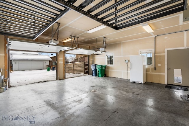 garage featuring white refrigerator and a garage door opener