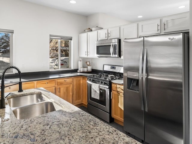 kitchen with white cabinets, sink, light stone counters, and stainless steel appliances