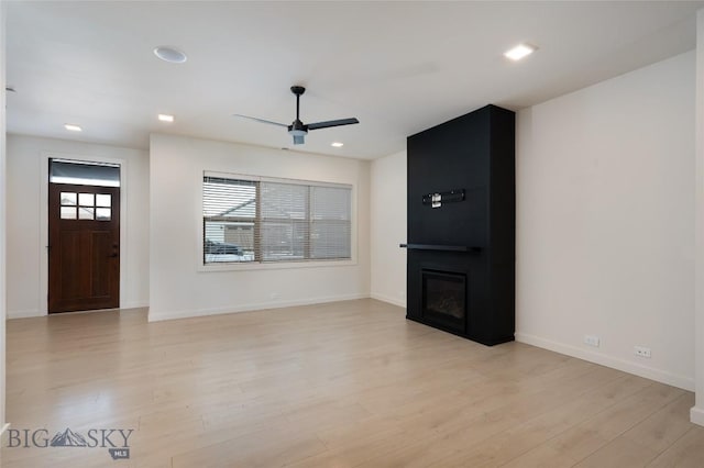 interior space with ceiling fan, light wood-type flooring, and a fireplace