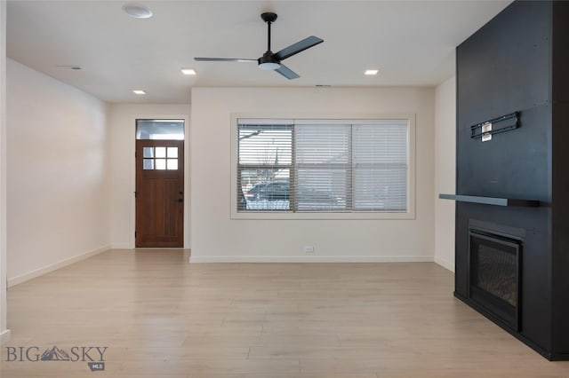 unfurnished living room with ceiling fan, a fireplace, and light hardwood / wood-style flooring