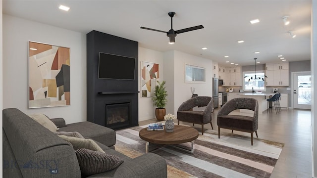 living room with sink, a large fireplace, ceiling fan, and light wood-type flooring