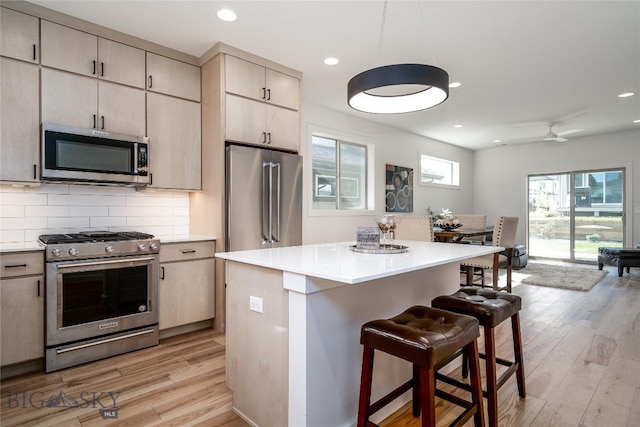 kitchen featuring a breakfast bar, stainless steel appliances, light hardwood / wood-style floors, a kitchen island, and decorative backsplash