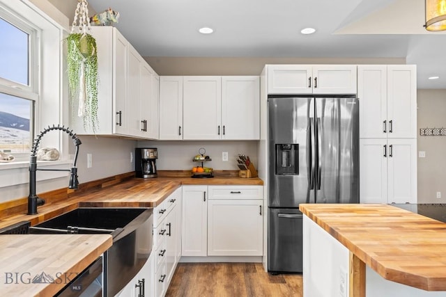 kitchen featuring white cabinets, wooden counters, and stainless steel refrigerator with ice dispenser