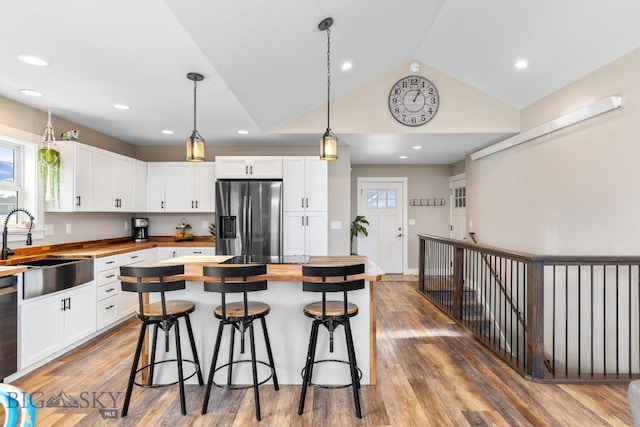 kitchen featuring sink, decorative light fixtures, white cabinets, stainless steel fridge with ice dispenser, and butcher block countertops