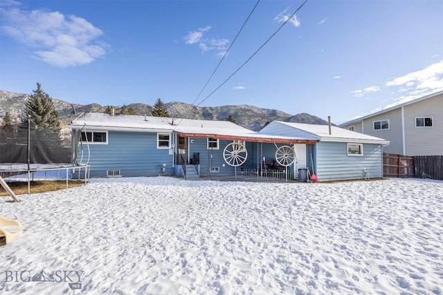 snow covered house with a mountain view and a trampoline