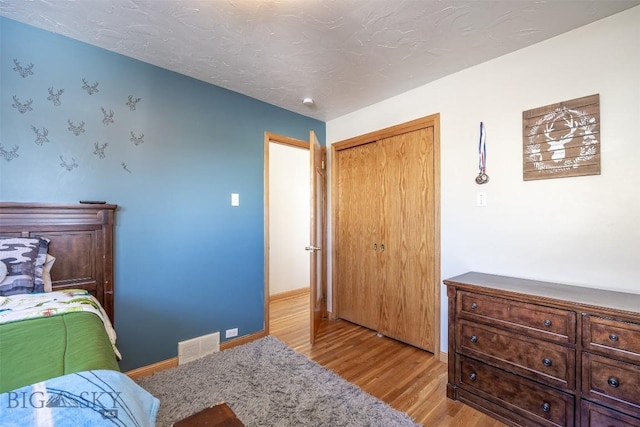 bedroom with a textured ceiling, a closet, and light wood-type flooring