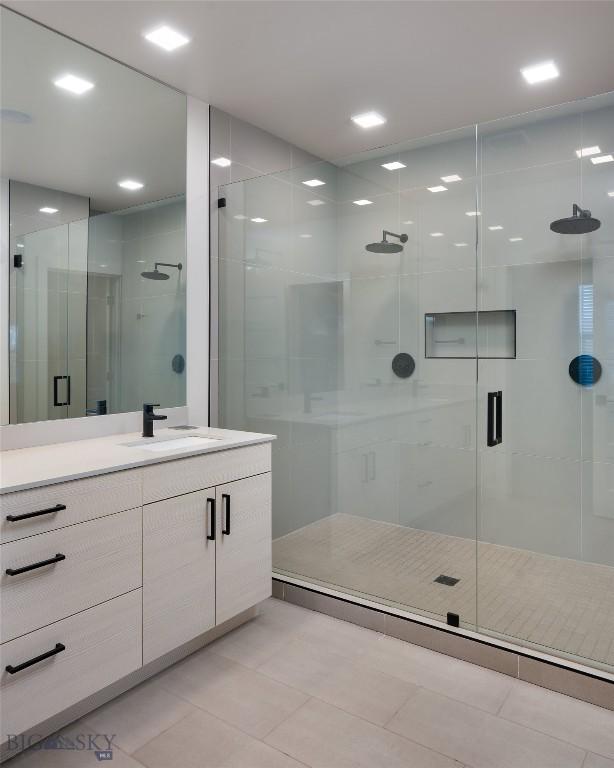 bathroom featuring tile patterned flooring, walk in shower, and vanity