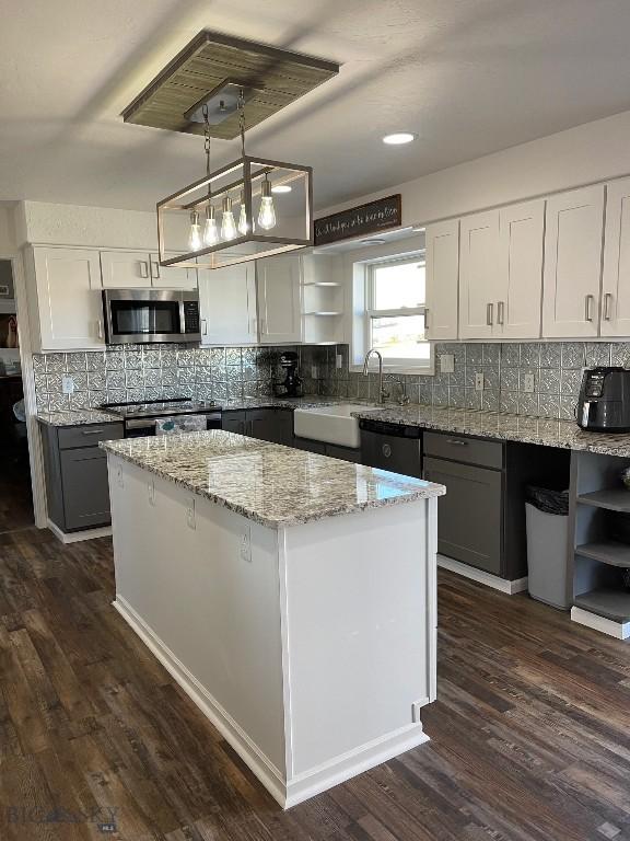 kitchen featuring pendant lighting, white cabinetry, a center island, and appliances with stainless steel finishes