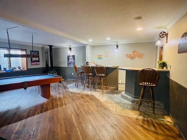 playroom with pool table, wood-type flooring, a wood stove, indoor bar, and ornamental molding