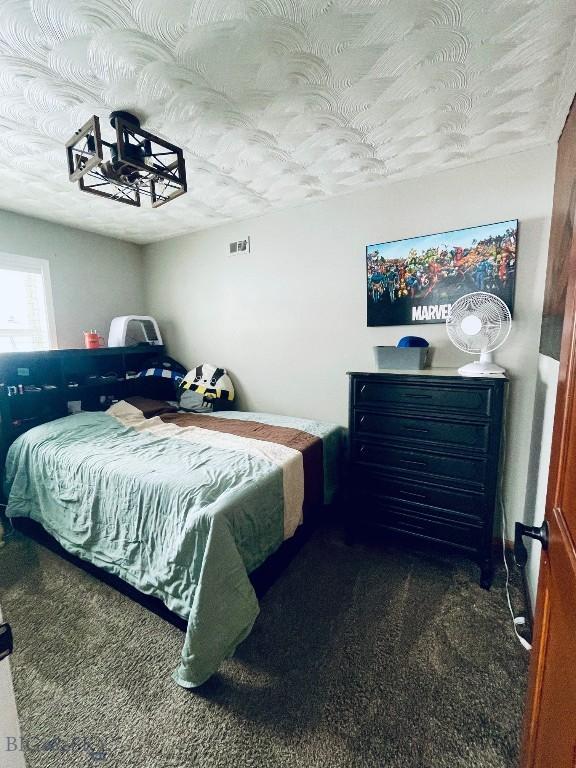 bedroom with dark carpet and a textured ceiling