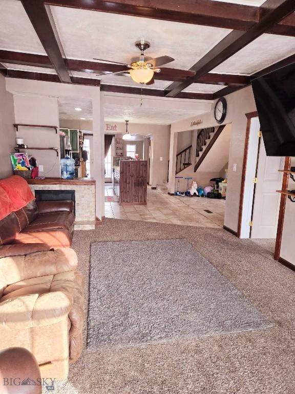 tiled living room with ceiling fan, beamed ceiling, and coffered ceiling