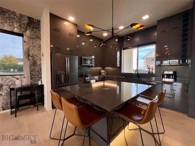 kitchen featuring modern cabinets, a kitchen breakfast bar, and appliances with stainless steel finishes