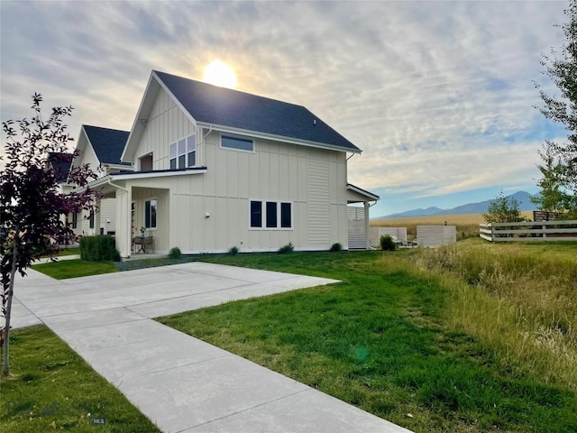 rear view of property with a mountain view and a lawn