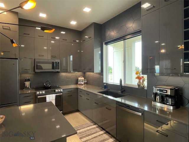 kitchen featuring a sink, gray cabinetry, stainless steel appliances, modern cabinets, and tasteful backsplash