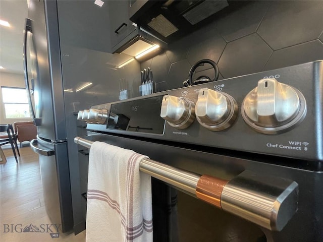 interior details with light wood-type flooring, range, and decorative backsplash