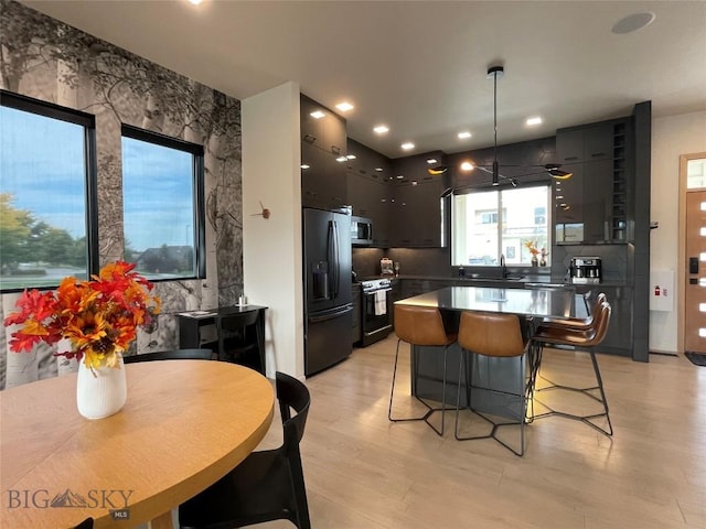 kitchen with stainless steel microwave, a breakfast bar area, range with electric stovetop, black fridge with ice dispenser, and modern cabinets