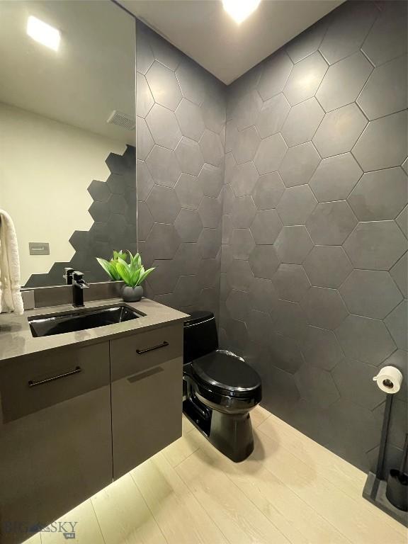 bathroom with vanity, toilet, and tile walls