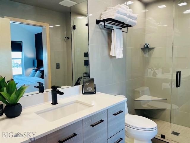 ensuite bathroom featuring connected bathroom, vanity, a shower stall, and toilet