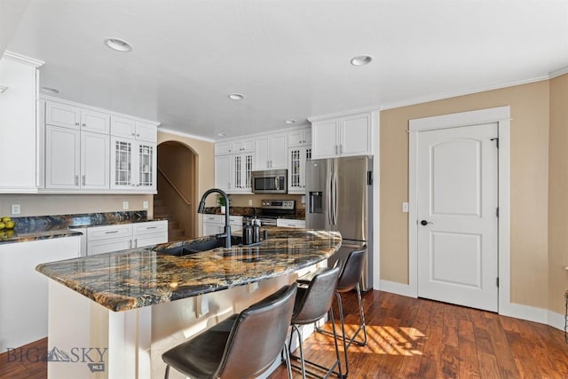 kitchen with white cabinetry, stainless steel appliances, an island with sink, sink, and a breakfast bar