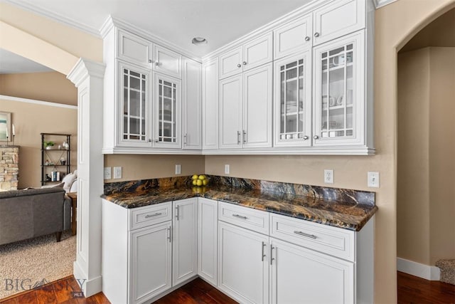 kitchen featuring dark wood-type flooring, white cabinetry, crown molding, and dark stone counters