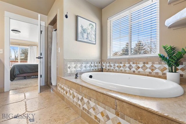 bathroom with a healthy amount of sunlight and a relaxing tiled tub